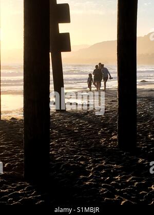 Family enjoying an evening strolling along the seaside near a pier. West coast, California Stock Photo