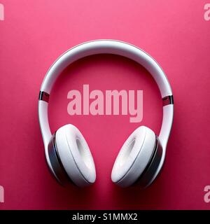 A set of white wireless headphones on a rich pink background Stock Photo