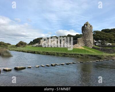 The 12th Century Ogmore Castle, South Wales, with stepping stones across the river Ogmore Stock Photo