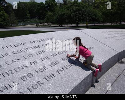 Little girl reading JFK speech at Kennedy grave Arlington National cemetery, Virginia USA Stock Photo
