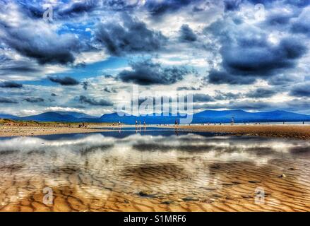 Clouds reflected in pool of water at low tide on Newborough beach on Anglesey Stock Photo