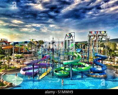 Storm clouds are brewing over a large Water Park that has numerous and varied water slides. It's summer holidays and people are out on vacation. Photo Credit - © COLIN HOSKINS. Stock Photo