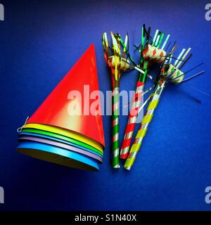 A bright colourful shot of party hats and noise makers on a blue background Stock Photo