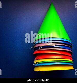 A bright colourful detail shot of a stack of party hats on a blue background Stock Photo