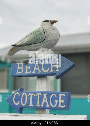 Wooden seagull sitting on beach cottage sign Stock Photo