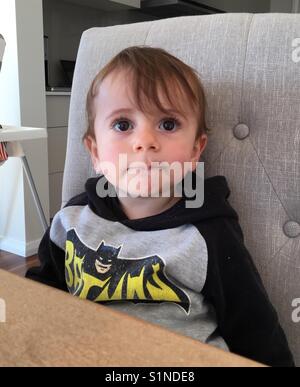 Serious little boy sitting on a chair. Stock Photo