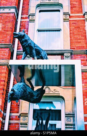 Inversion (2010) by Eldon Garnet, James Cooper Mansion, Toronto, Ontario, Canada. Two bronze wolves, one upright, the other inverted and mirrored, elevated on a stainless steel tower. Stock Photo