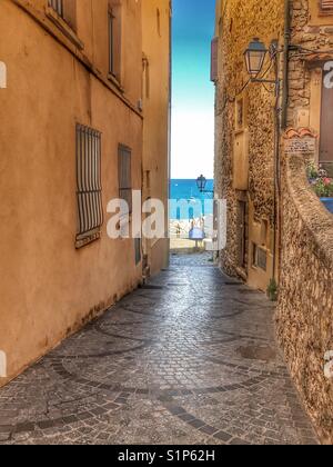 View of the Mediterranean sea through a narrow street. Stock Photo