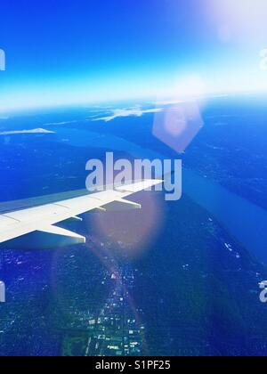 Wing of  passenger jet aircraft in flight taken from passenger seat window, USA Stock Photo