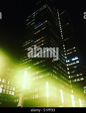 Green hazy lights glowing in front of an office block at night. Stock Photo