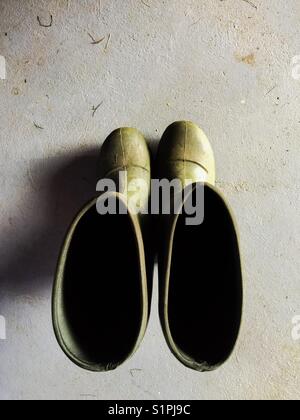 Dirty, green work boots shot from above on concrete floor Stock Photo