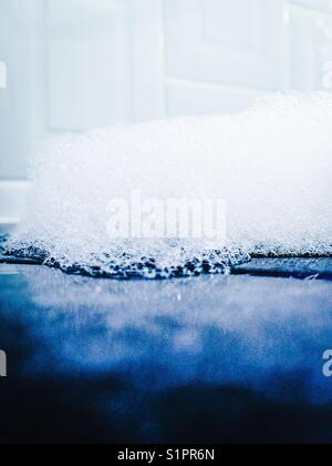 Bubbles on dark bathroom tile with white tile in background Stock Photo