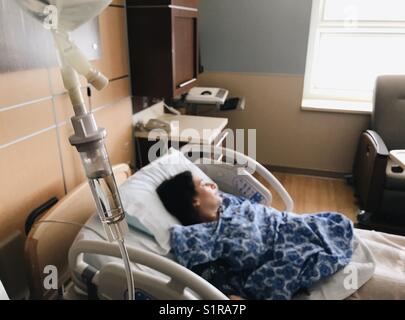 A pregnant woman on a hospital bed connected to an intravenous drip. Stock Photo