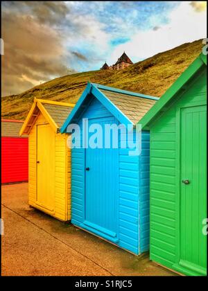 Brightly coloured Beach Huts near the seaside at Whitby, Yorkshire, England. It is nearing sunset, so people have returned to their accommodation. Photo Credit - © COLIN HOSKINS. Stock Photo