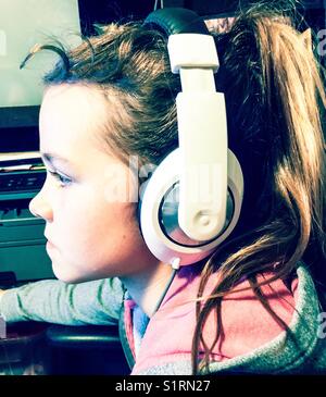 Profile view of girl wearing large white headphones Stock Photo