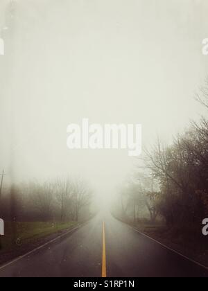 Rainy view of looking down empty road that disappears into fog in rural Ontario, Canada Stock Photo