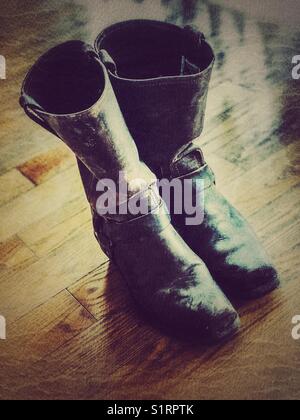Rustic old pair of worn and scuffed brown cowgirl boots on wooden floor Stock Photo