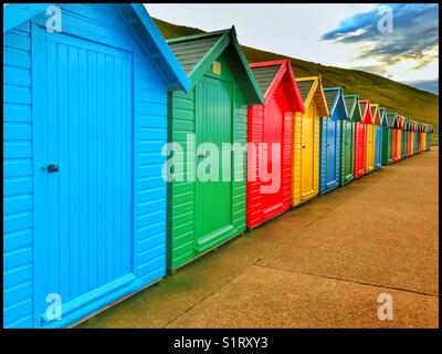 A row of colourful beach huts along the shore line at Whitby, Yorkshire, England. All the huts are closed and everybody has gone. Photo Credit - © COLIN HOSKINS. Stock Photo