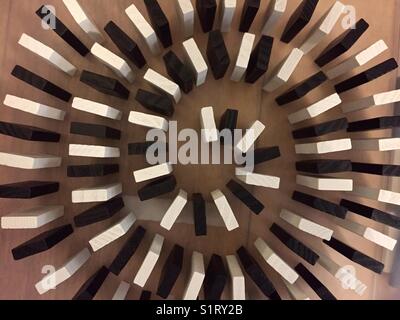 Black and white domino blocks lined up in a circular spiral ready to knocking over takes from above Stock Photo