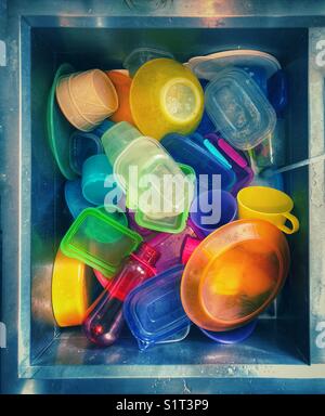 Stainless steel sink full of children’s plastic dishes to be washed Stock Photo