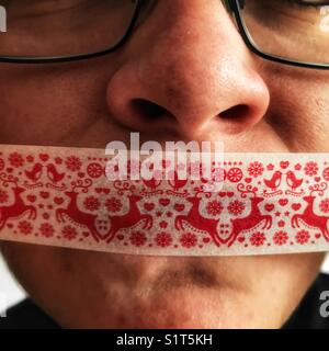 Young woman’s face with Christmas gift tape over her mouth Stock Photo