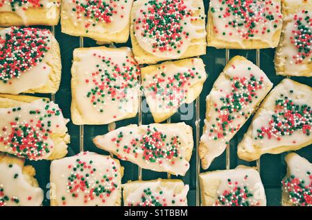Homemade sugar cookies glazed with Christmas coloured sprinkles made by a child Stock Photo