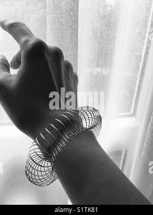Lady wearing a silver bracelet against white curtains Stock Photo