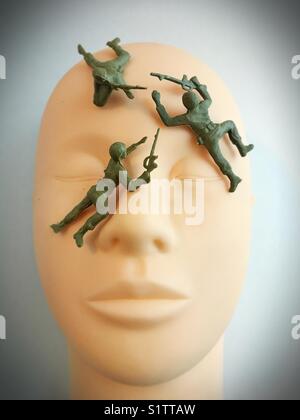 Toy plastic soldiers on plastic human face. Stock Photo