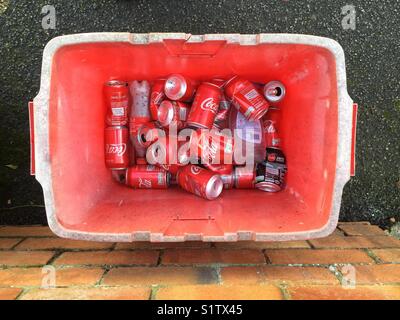 Empty Coca Cola cans in a red recycling container. Builth Wells, Powys, Wales, UK. Stock Photo