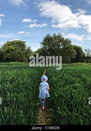 Young girl walking through arable field Stock Photo