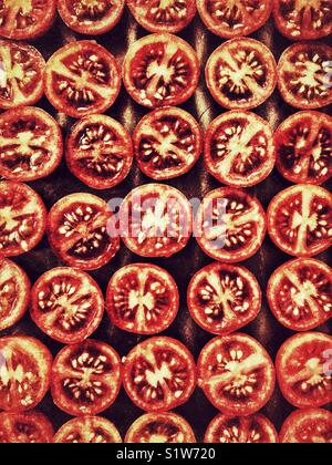 Cherry tomatoes, cut in half, on a baking tray ready to go in the oven to be roasted Stock Photo