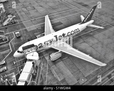 A monochrome image of an aerial view looking down on an EasyJet Airbus aircraft as it sits on the tarmac of an airport departure gate. Photo Credit - © COLIN HOSKINS.