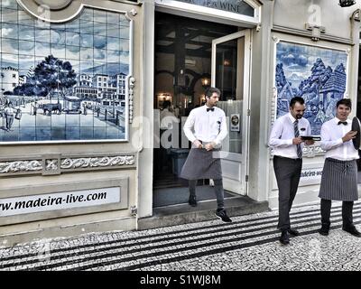 Waiters in the doorway, plus blue and white handmade glazed tiled pictures, azulejos, decorating the facade of The Ritz Hotel, Funchal, Madeira, Portugal Stock Photo