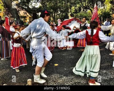 Group of young musicians and folk dancers in traditional costumes performing in the Municipal Gardens in the run up to Christmas, Funchal, Madeira, Portugal Stock Photo