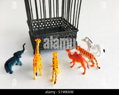 Plastic toy animals facing a cage. Stock Photo