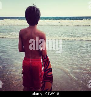 Boy waiting for perfect wave for skim boarding Stock Photo