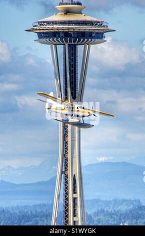 Sea plane from Kenmore Air passing right in front of the space needle at a low altitude as it is getting ready to land at Lake Union in Seattle Washington Stock Photo