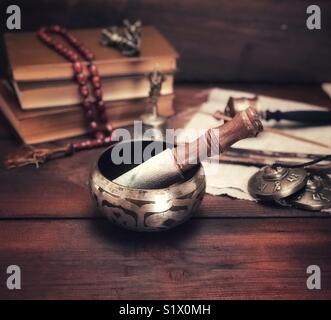 singing a copper bowl and a wooden stick on a brown wooden table, vintage toning Stock Photo