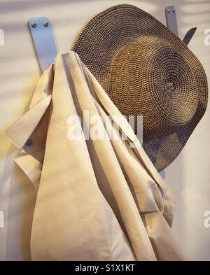Hat and light jacket hanging on coat room pegs. Stock Photo