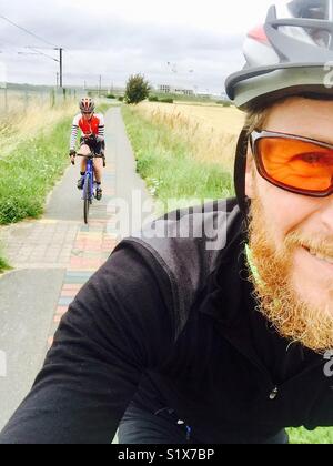Man and woman cycling along a cycle path in England Stock Photo