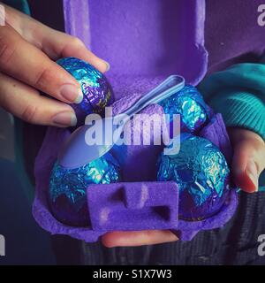 Girl taking a Cadbury chocolate egg out of a purple egg carton Stock Photo