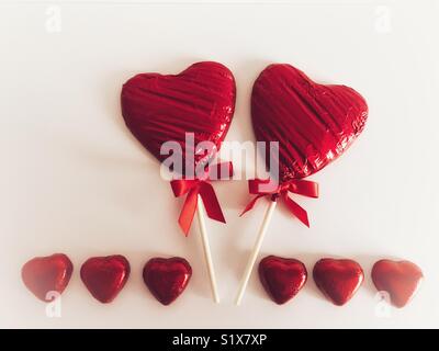 Valentine’s Day, red chocolate heart shaped lollipops and red chocolate hearts on a white background with copy space Stock Photo