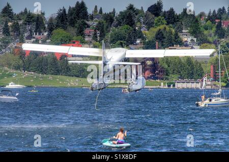 Seaplane taking off on Lake Union over the top of a kayaker Stock Photo