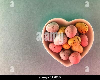 Chocolate Easter eggs in a heart shaped ceramic dish Stock Photo