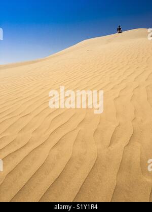 Tourist sitting on top of a sand dune in the Rub al-Khali, (Empty Quarter) desert in Dhofar, Oman. Stock Photo