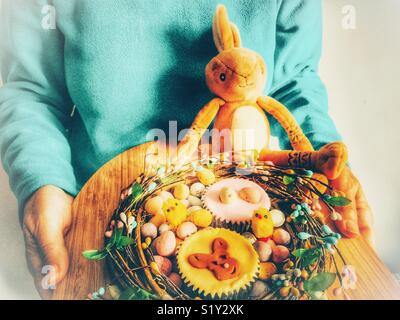 Woman holding a decorative tray of Easter eggs and cupcakes, Easter special treats Stock Photo