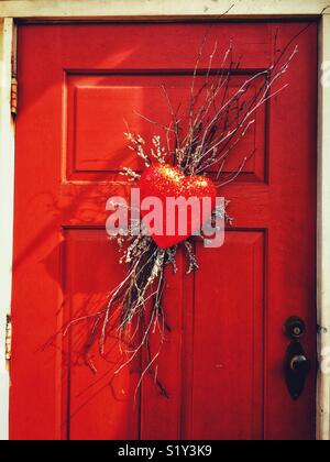 Glittery red heart wreath on red door Stock Photo