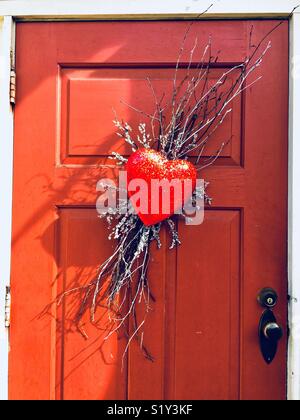 Glittery red heart wreath on orange red door Stock Photo