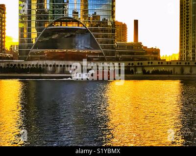 Golden colors surround a tugboat crossing the Chicago River at sunset. Stock Photo