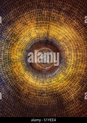 Top view into a oval sink, looking straight down at the plug hole. With a weathered beaten copper look to the sink itself. Stock Photo